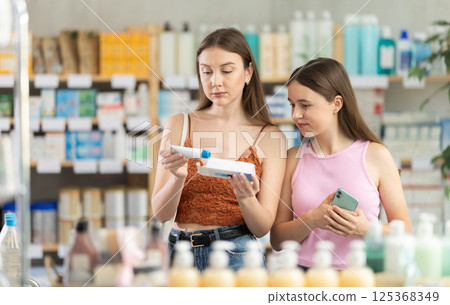 Woman with teen girl are busy choosing ointment for bruises at pharmacy 125368349