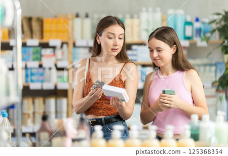 Woman with daughter choosing pills in pharmacy Woman with daughter choosing pills in pharmacy 125368354