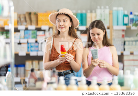 woman with a child chooses sunscreen in pharmacy 125368356