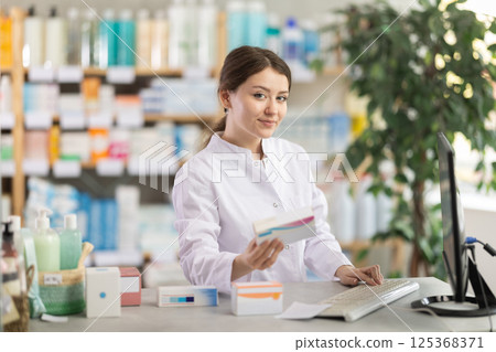 Female pharmacist brings new products into the computer 125368371