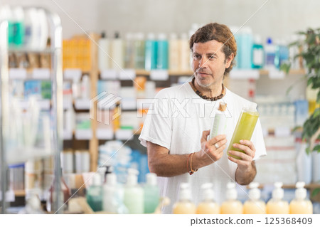 man chooses a dandruff shampoo at the pharmacy man chooses a dandruff shampoo at the pharmacy 125368409