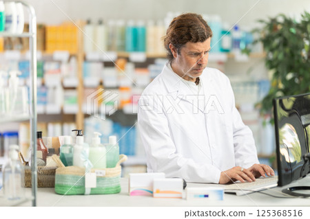 Male pharmacist working at computer in pharmacy Male pharmacist working at computer in pharmacy 125368516
