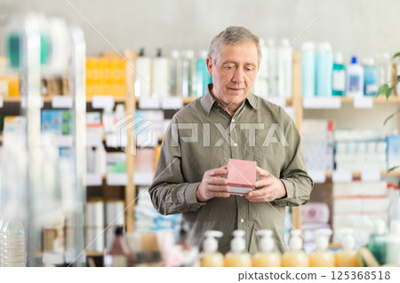 Elderly man in a pharmacy chooses pills Elderly man in a pharmacy chooses pills 125368518