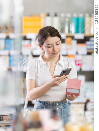 Girl scans code on package of ointment to check expiration date 125368532