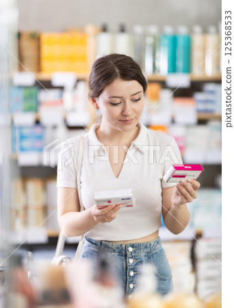 Girl in summer clothes buys paracetamol medicine at pharmacy 125368533