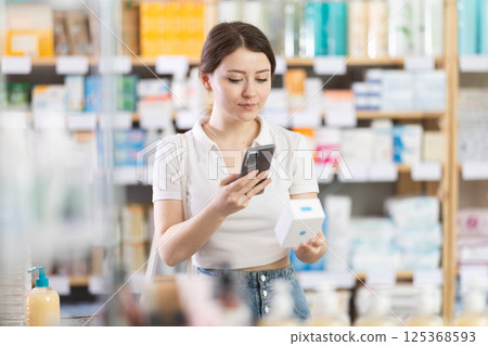 Female customer scanning QR code on pills with phone in drugstore 125368593