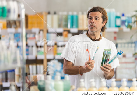 Man choosing a set of toothbrushes at the pharmacy 125368597