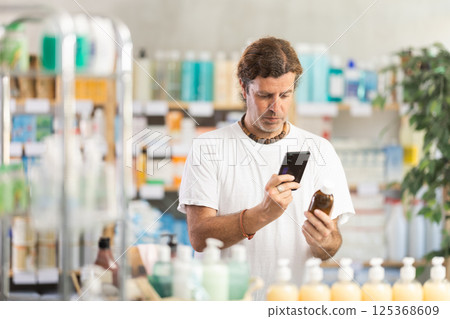 Man scans for mobile medicinal syrup in pharmacy Man scans for mobile medicinal syrup in pharmacy 125368609
