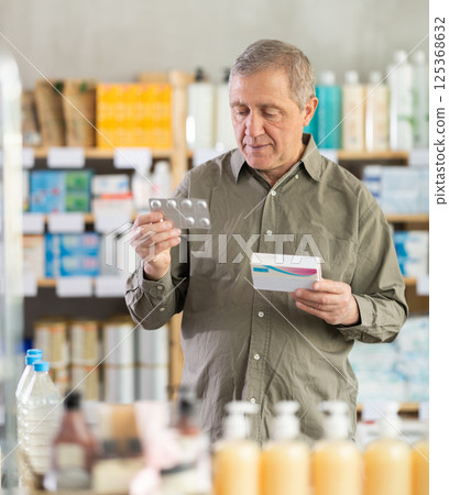Senior man buys pills at pharmacy Senior man buys pills at pharmacy 125368632