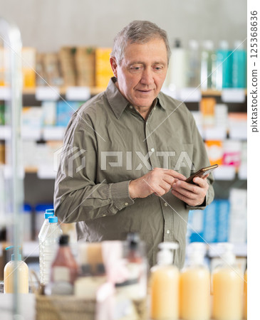 Senior man with phone is shopping in pharmacy Senior man with phone is shopping in pharmacy 125368636