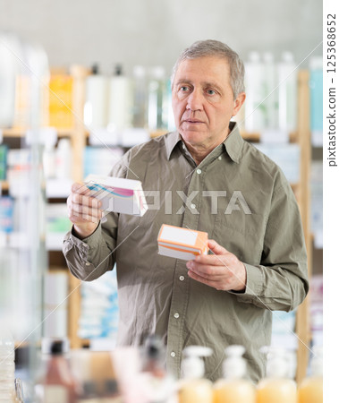Senior man buys pills at pharmacy Senior man buys pills at pharmacy 125368652