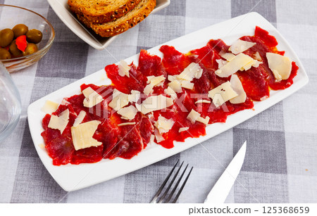 Beef carpaccio cold appetizer with parmesan, on plate 125368659