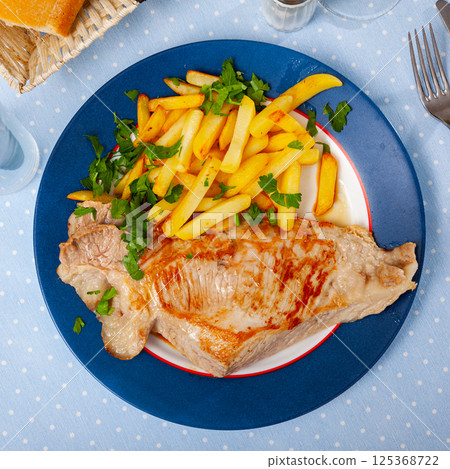 Fried pork tenderloin with potatoes, served with greens 125368722