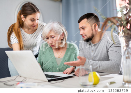 Young couple helping elderly woman use laptop 125368739