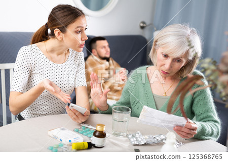 Young wife and an elderly mother discuss what medicines are needed for sick husband Young wife and an elderly mother discuss what medicines are needed for sick husband 125368765
