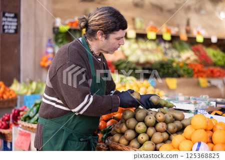 Man shop seller puts pear goods on display case 125368825