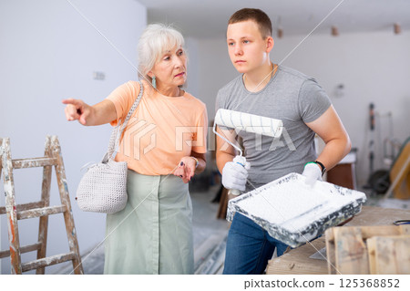 Senior woman discussing work details with teenager boy in constrcuction site 125368852