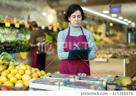 Woman store employee with folder of documents takes inventory in vegetable store 125368878