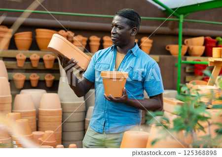 African american man choosing pots for flowers and trees in gardening market African american man choosing pots for flowers and trees in gardening market 125368898