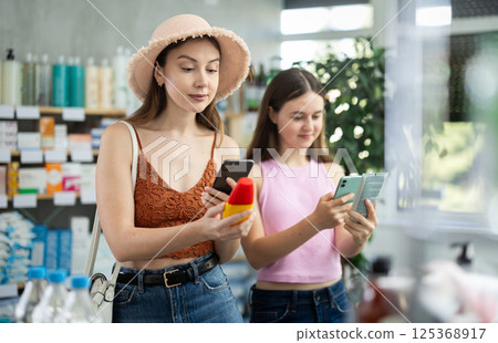 Woman with daughter scanning qr code of sunscreen Woman with daughter scanning qr code of sunscreen 125368917