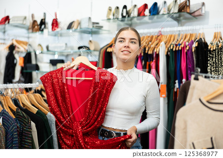 Young woman choosing dress in store Young woman choosing dress in store 125368977