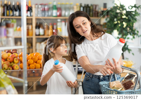 Child girl with mother choose consider milk snacks. Child girl with mother choose consider milk snacks. 125369017
