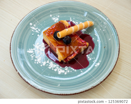 Slice of delicious cake with cheese mousse with blueberry topping on plate. Spanish dessert tarta de queso con arandano 125369072