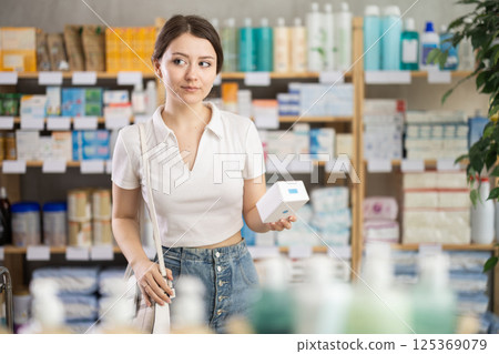 Girl in summer clothes looking for medicine in pharmacy 125369079