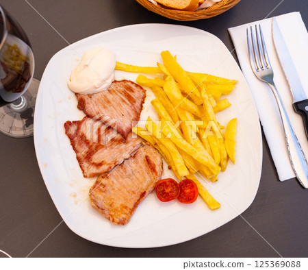 On plate are pieces of fried pork tenderloin,garnished with French fries. On plate are pieces of fried pork tenderloin,garnished with French fries. 125369088