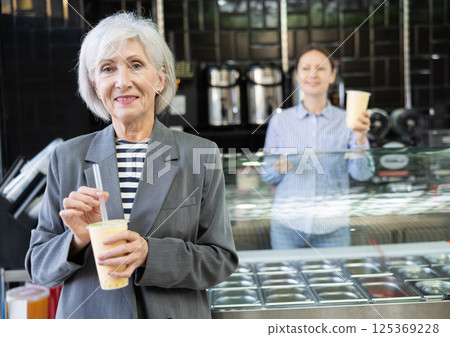 Senior woman drinks tonic bubble tea through straw Senior woman drinks tonic bubble tea through straw 125369228