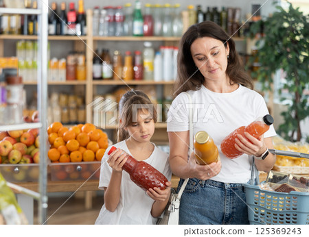 Child girl with mother choose consider juice Child girl with mother choose consider juice 125369243