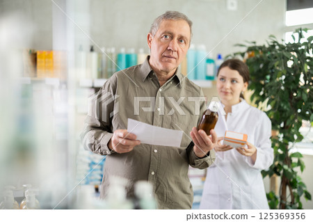 Man choosing pills with help from pharmacist Man choosing pills with help from pharmacist 125369356