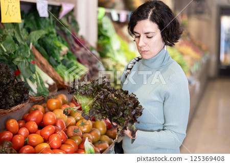 Portrait of woman buying arugula in grocery shop 125369408