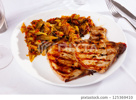 Tasty meat pork served with braised cabbage on served table 125369410