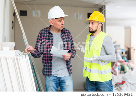 Foreman and confused builder counting building materials Foreman and confused builder counting building materials 125369421