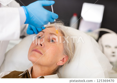 Elderly wman receiving procedure of face mesotherapy at cosmetology clinic 125369470