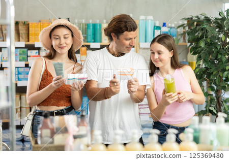 Man with wife and teen daughter customers in drugstore choose with different products 125369480