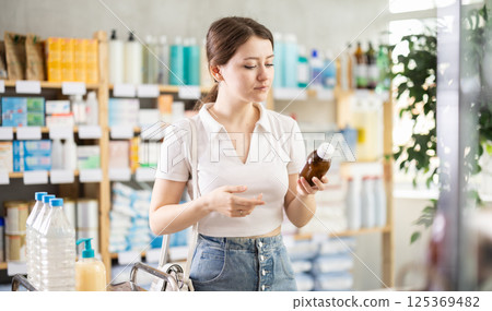 Young woman chooses syrup at pharmacy 125369482