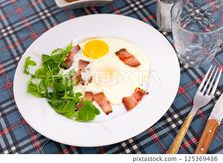 Delicious breakfast with scrambled eggs, bacon and arugula Delicious breakfast with scrambled eggs, bacon and arugula 125369486