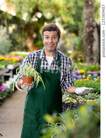 Portrait of handsome male florist selling potted flowers in shop Portrait of handsome male florist selling potted flowers in shop 125369487
