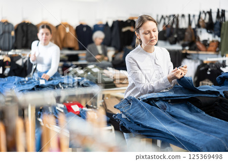 Adult woman choosing jeans in store Adult woman choosing jeans in store 125369498