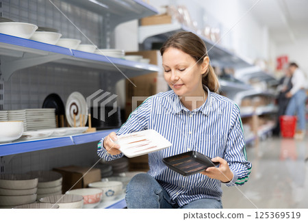 Female shopper choosing square ceramic Asian style plates in store 125369519