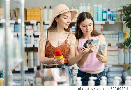 Woman and daughter scanning sunscreen packaging barcode 125369554