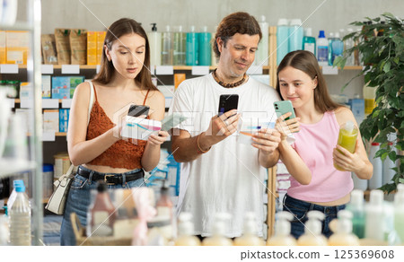 Man with wife and teen daughter in pharmacy scans QR code on good Man with wife and teen daughter in pharmacy scans QR code on good 125369608