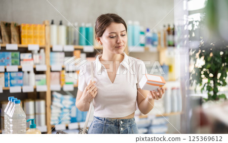 Girl in summer clothes looking for medicine in pharmacy 125369612