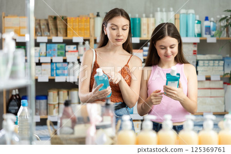 Woman with daughter choosing mouthwash in pharmacy Woman with daughter choosing mouthwash in pharmacy 125369761