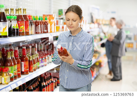 Woman reading label on ketchup bottle at Asian grocery store 125369763