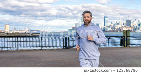 Man sportsman running for exercise in active wear. Sportsman jogger running. Morning sport workout runner running. Sport runner in Manhattan. Sportsman in New York. Copy space banner Man sportsman running for exercise in active wear. Sportsman jogger running. Morning sport workout runner running. Sport runner in Manhattan. Sportsman in New York. Copy space banner 125369786