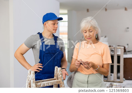 Mature woman pays a fifteen-year-old worker Mature woman pays a fifteen-year-old worker 125369803