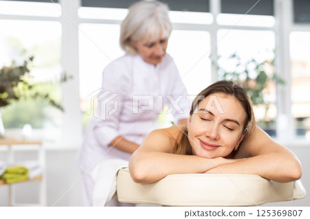 Young woman relaxing in spa center during professional back massage 125369807